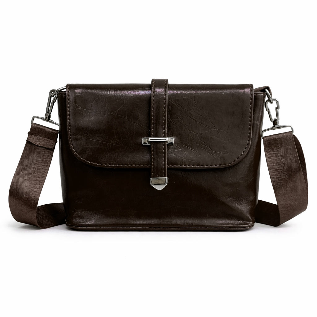 A classic women's crossbody bag in premium leather, featuring a stylish flap design, a distinctive silver metal clasp, and a wide, adjustable strap.