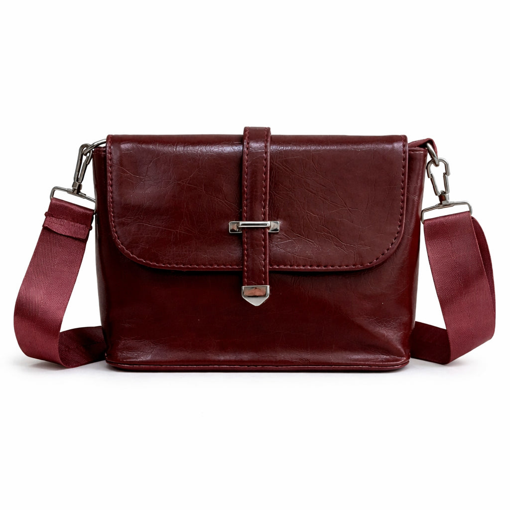 A classic women's crossbody bag in premium leather, featuring a stylish flap design, a distinctive silver metal clasp, and a wide, adjustable strap.