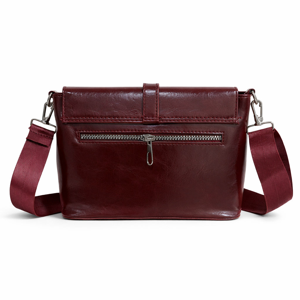 A classic women's crossbody bag in premium leather, featuring a stylish flap design, a distinctive silver metal clasp, and a wide, adjustable strap.