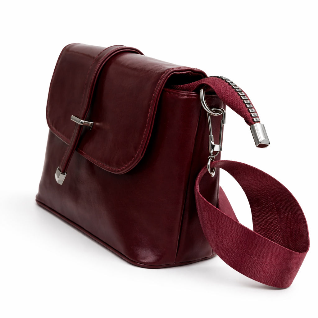 A classic women's crossbody bag in premium leather, featuring a stylish flap design, a distinctive silver metal clasp, and a wide, adjustable strap.