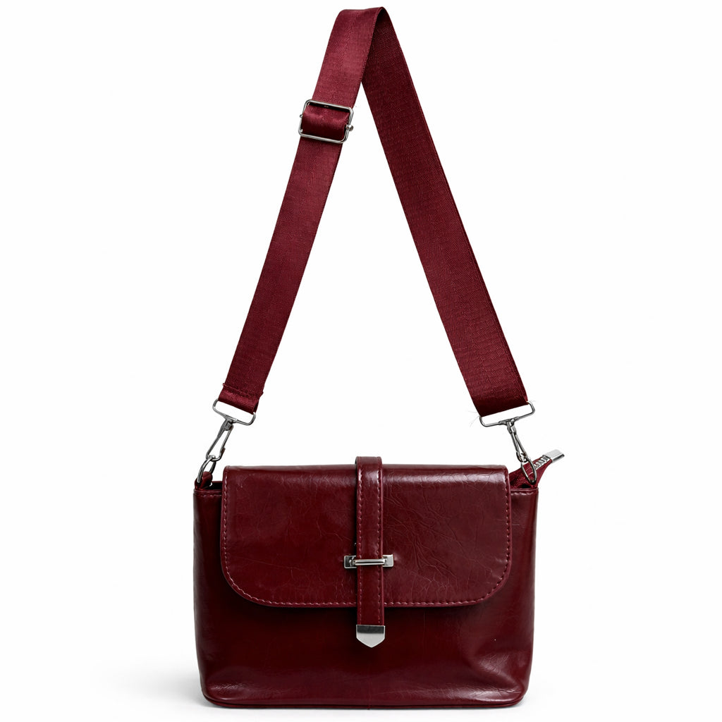 A classic women's crossbody bag in premium leather, featuring a stylish flap design, a distinctive silver metal clasp, and a wide, adjustable strap.
